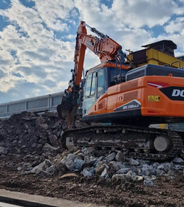 Macchinario da cantiere che esegue una demolizione industriale su struttura in cemento.